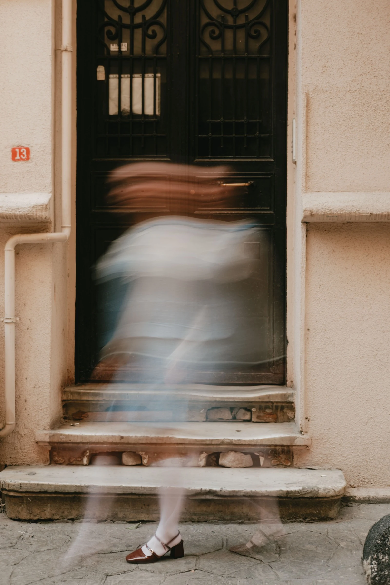 A passerby captured in motion against a dark doorway